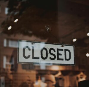 Classic closed sign hanging in front of a store window.